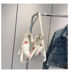 Vue détaillée du sac cabas en velours côtelé blanc avec broderie rouge et bandoulière