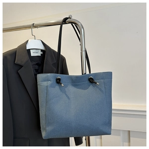 Détail du sac fourre-tout en denim bleu clair avec fines bretelles et nœud déco