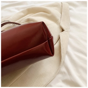 Détail du sac cabas en cuir bordeaux montrant les coutures fines et la bandoulière