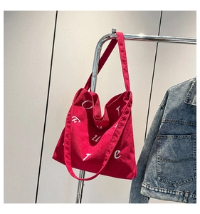Détail du sac cabas en velours côtelé rouge avec broderie FUTURE sur cintre en métal