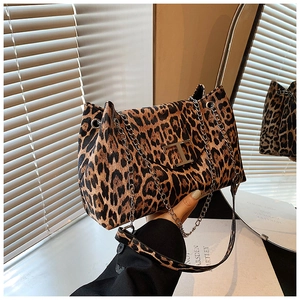 Detail of metal T-shaped logo and leopard print texture on a large capacity shoulder bag