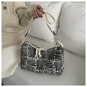 Detail view of black and white patterned tote bag with adjustable strap and dual zippers