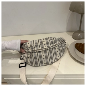 Détail d'un sac de poitrine demi-lune tissé à rayures avec bandoulière réglable sur table