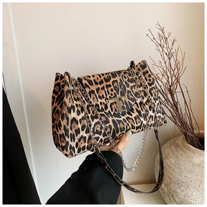 Detail of leopard print handbag featuring a gold T-buckle and chain shoulder strap