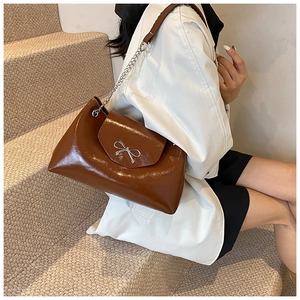 Sac bandoulière marron brillant avec nœud argenté porté avec blazer et jupe noire