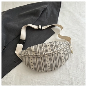 Détail d'un sac bandoulière tissé à rayures verticales noires et blanches et sangle