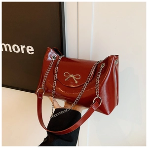 Gros plan du sac cabas bordeaux brillant avec un détail élégant de nœud en métal