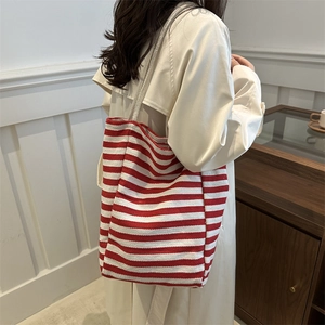 Large striped canvas tote bag with woven rope handles shown on shoulder by model