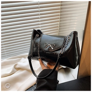 Détail du sac fourre-tout en cuir verni brillant avec nœud argenté et chaîne