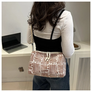 Detail view of woven striped tote bag showing dual zipper design and adjustable strap