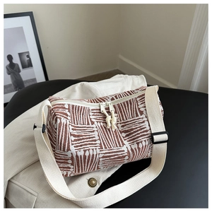 Detail of striped cylinder tote bag showing dual zippers and adjustable canvas strap
