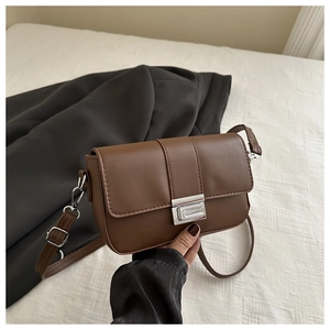 Dettaglio borsa quadrata in pelle marrone con chiusura in metallo argento e cuciture fini