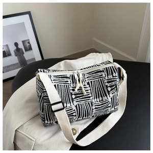Detailed shot of striped canvas tote bag texture with adjustable strap on beige fabric