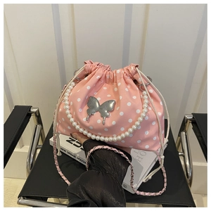 Close-up of pink polka dot bucket bag featuring pearl handle and silver butterfly clasp