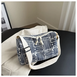 Detail of blue and white striped tote bag showing double zippers and adjustable wide strap