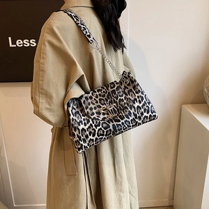 Leopard print crossbody bag with gold T-clasp and chain strap on a chic trench coat