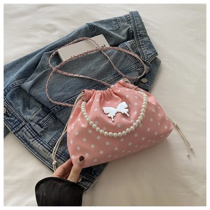 Detail of pink polka dot drawstring bucket bag with pearl handle and butterfly charm