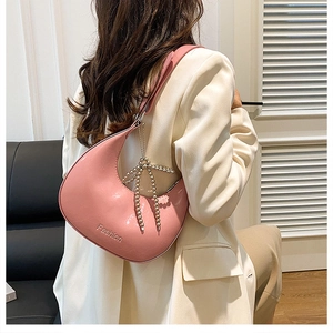 Detail of pink crescent hobo bag with Fashion print and pearl bow charm on shoulder
