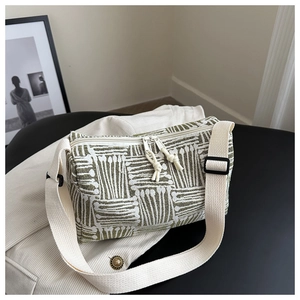 Detail of green and white striped jacquard barrel bag with a wide canvas shoulder strap