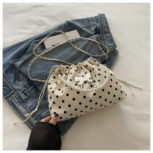 Detail of drawstring bucket bag featuring black polka dots and silver butterfly hardware