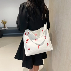 Sac cabas blanc en velours côtelé avec broderies rouges porté sur une robe noire