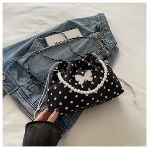 Detail of black and white polka dot bucket bag with silver butterfly and pearl handle