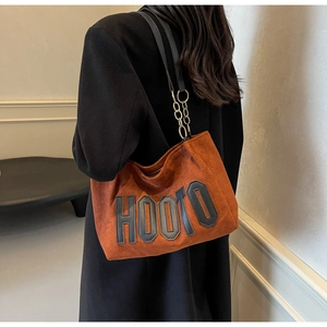 Close-up of HOOTO letter embroidery and chain detail on caramel matte tote bag