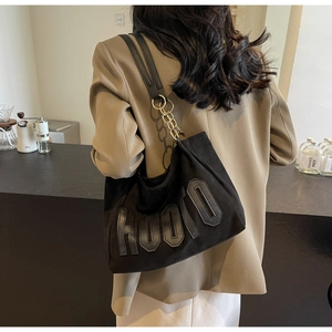 Detail of a black tote bag with HOOFO lettering and gold chain strap on a model