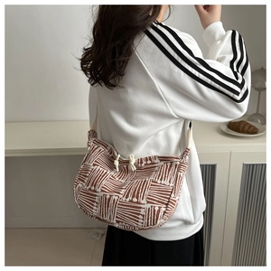 Side view of a striped large capacity tote bag worn by a model in a cozy home setting