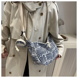 Close-up of blue and white striped knit fabric texture on a shoulder bag with mini pouch