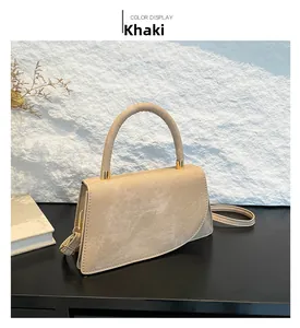 Dettaglio borsa in pelle kaki con patta asimmetrica e finiture in metallo dorato lucido