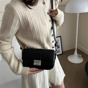 Borsa a tracolla nera minimalista con chiusura argento indossata con cardigan beige