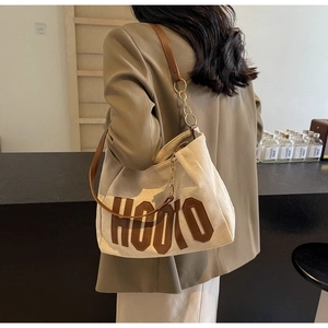 Detail of canvas tote with brown HOOTO leather applique and gold chain shoulder strap