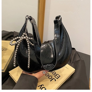 Detail of black crescent bag with wrinkled texture, Fashion logo and bow charm