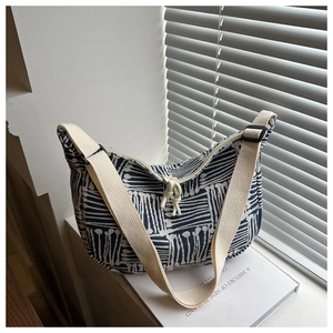 Close-up of a blue and white geometric canvas tote bag with a beige strap and zipper
