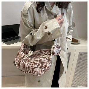Close-up of a brown woven crescent tote bag with matching small coin purse on a model