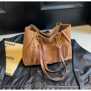 Close-up of brown suede tote bag with HOTO letter embroidery and gold chain strap