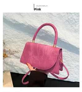 Dettaglio della borsa rosa con manico rotondo e trama martellata contro la roccia