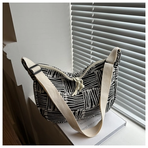 Detail of canvas tote bag with black and white abstract patterns and wide cotton strap