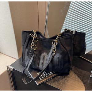 Detail of black faux suede tote bag with HOOO lettering and metal chain strap