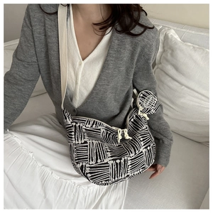 Close-up of black and white plaid tote bag with wide strap and matching round coin purse