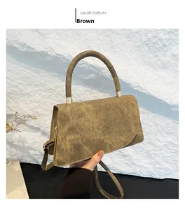 Dettaglio di una borsa a tracolla marrone vintage con texture opaca e fibbie dorate
