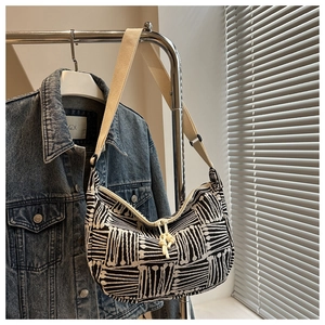 Detailed view of the black and white geometric pattern and woven strap on a crescent bag