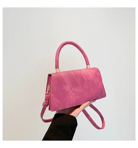 Dettaglio borsa fucsia in simil camoscio con finiture dorate e tracolla regolabile