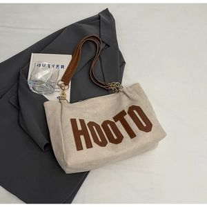 Detail of beige canvas tote with brown leather HOOTO patch and gold chain strap
