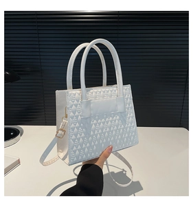 Détail d'un sac à main blanc avec texture géométrique en relief et boucles en métal doré