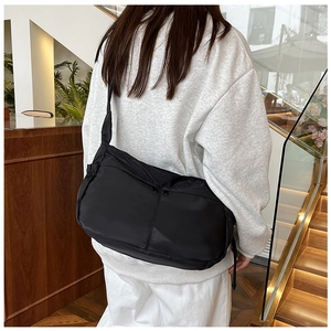 Detailansicht einer minimalistischen schwarzen Nylon-Tasche, getragen von einem Modell