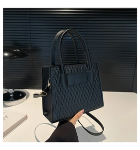 Détail d'un sac bandoulière noir avec texture matelassée et finitions métalliques dorées