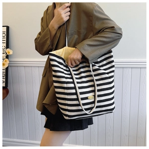 Close-up of striped canvas tote bag with cotton rope handles and handmade metal tag