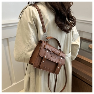 Detail of caramel brown PU leather crossbody bag with heart embossing and bow ornament